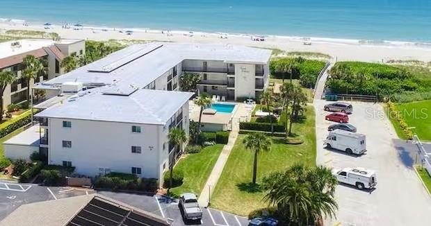 An aerial view of a multi-story beachfront condominium complex with a pool and parking lot — 504 FILLMORE AVENUE UNIT B8, CAPE CANAVERAL, FL