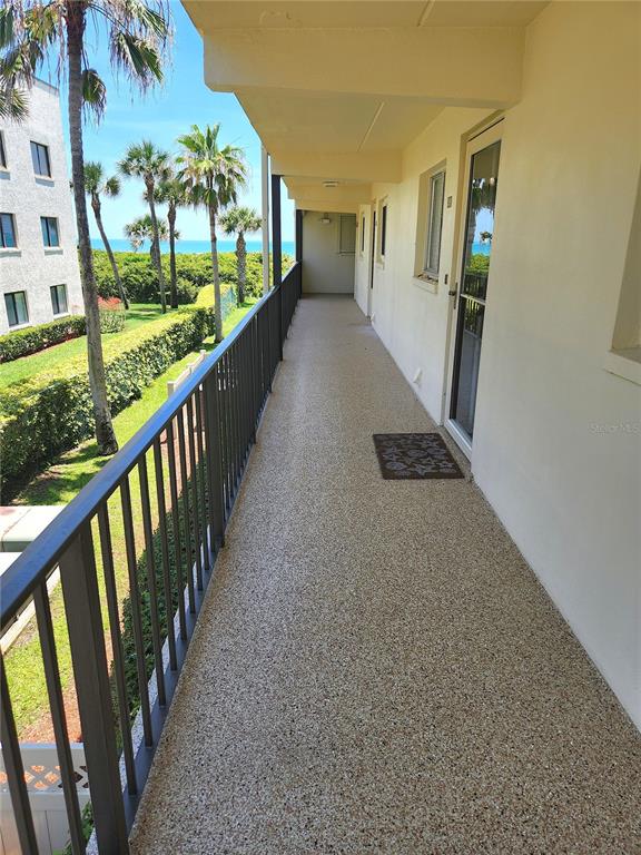 An outdoor walkway with a metal railing overlooks a grassy area and the ocean — 504 FILLMORE AVENUE UNIT B8, CAPE CANAVERAL, FL