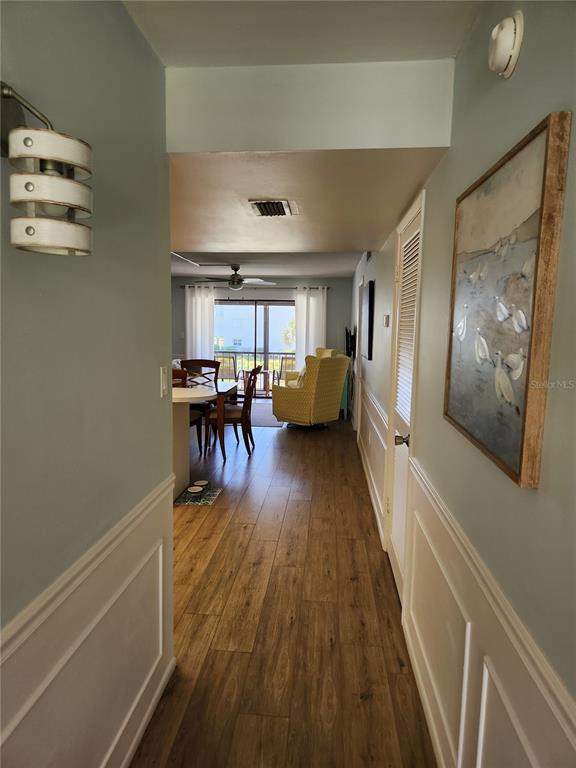 A hallway with light blue walls and wood-look flooring leads into an open living area — 504 FILLMORE AVENUE UNIT B8, CAPE CANAVERAL, FL