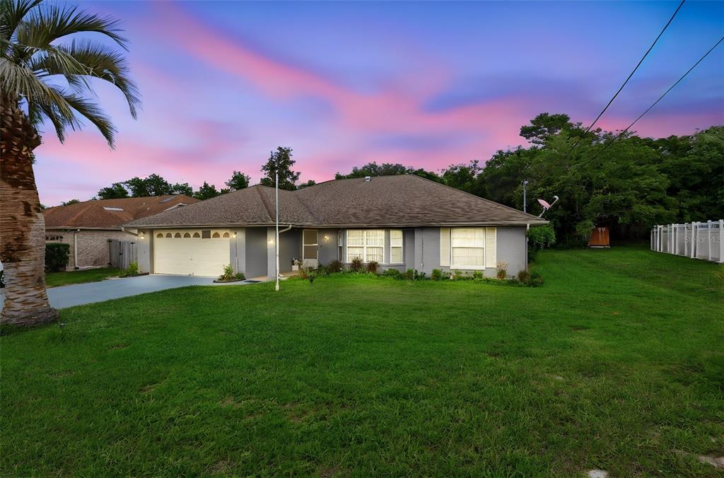 A single-story house with a two-car garage and a large front lawn at sunset — 2307 FITZPATRICK TERRACE, DELTONA, FL