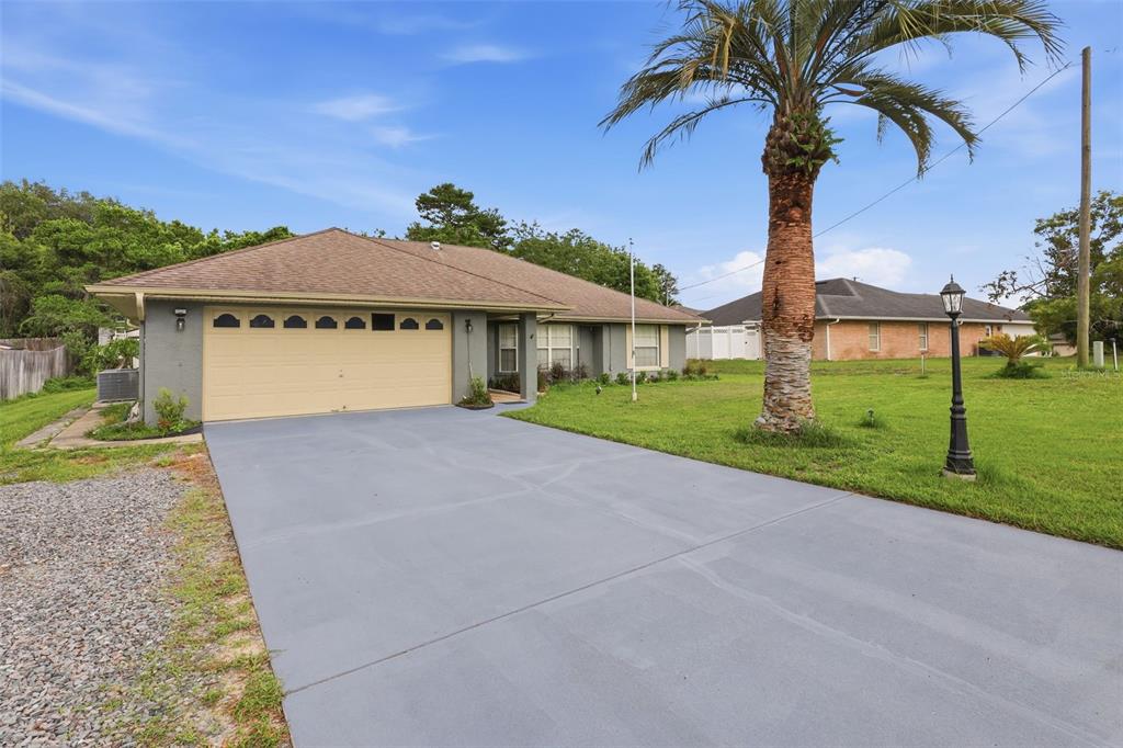 A single-story house with a beige garage door, gray exterior, and a large palm tree — 2307 FITZPATRICK TERRACE, DELTONA, FL