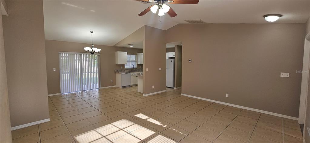 An open-concept living and dining area features beige tile flooring and a kitchen with white cabinets — 3740 SW SANTA BARBARA PLACE, CAPE CORAL, FL