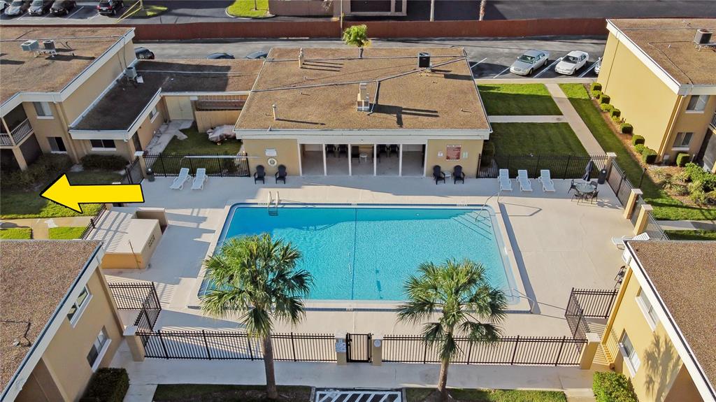An aerial view shows a rectangular swimming pool surrounded by a patio and apartment buildings — 1000 LAKE OF THE WOODS BOULEVARD UNIT C103, FERN PARK, FL