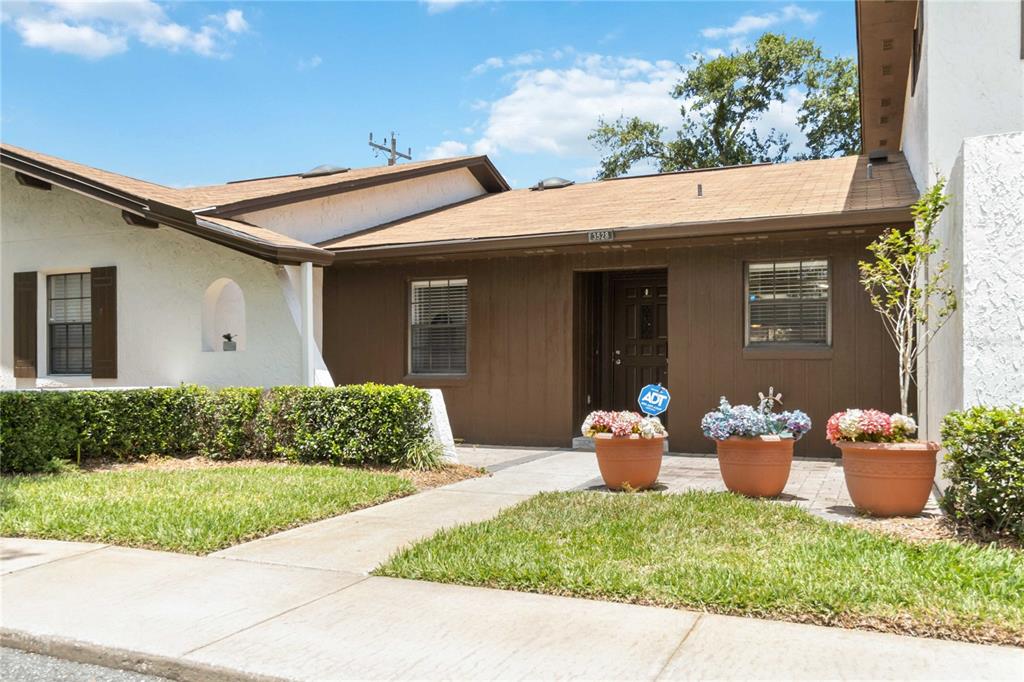 A brown-sided house exterior features a front entrance, a walkway, and three potted flower arrangements — 3528 BAY CT, ST CLOUD, FL