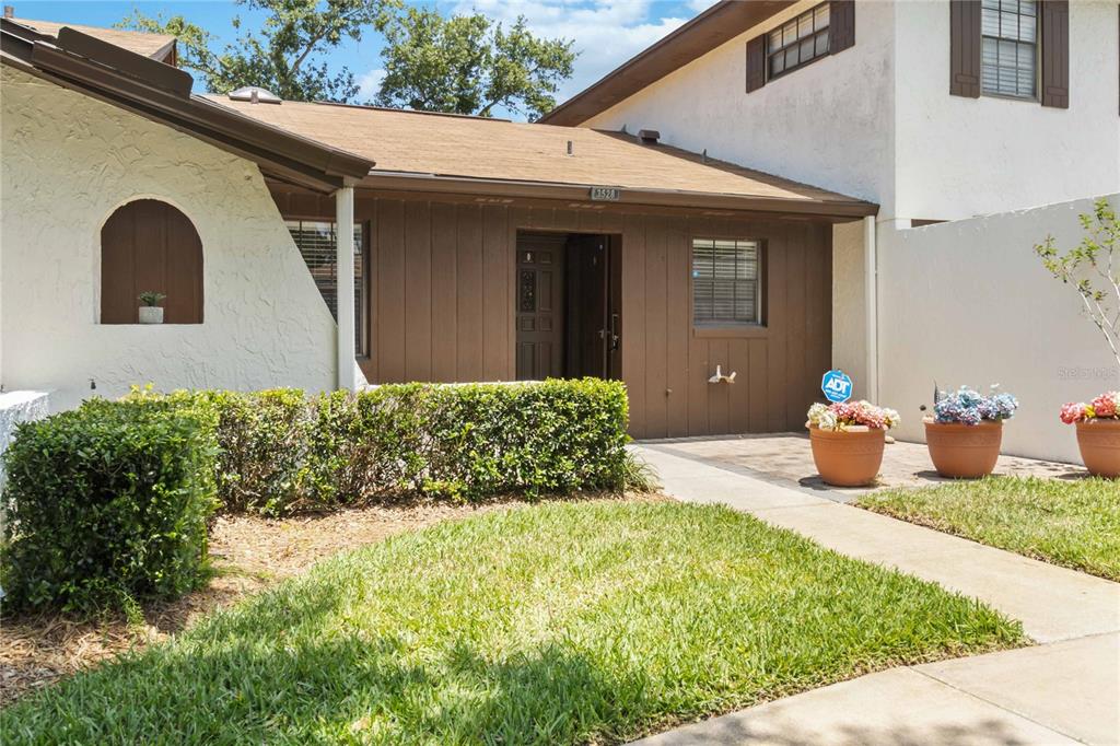 The exterior of a house features a brown wood-paneled entrance with potted flowers — 3528 BAY CT, ST CLOUD, FL