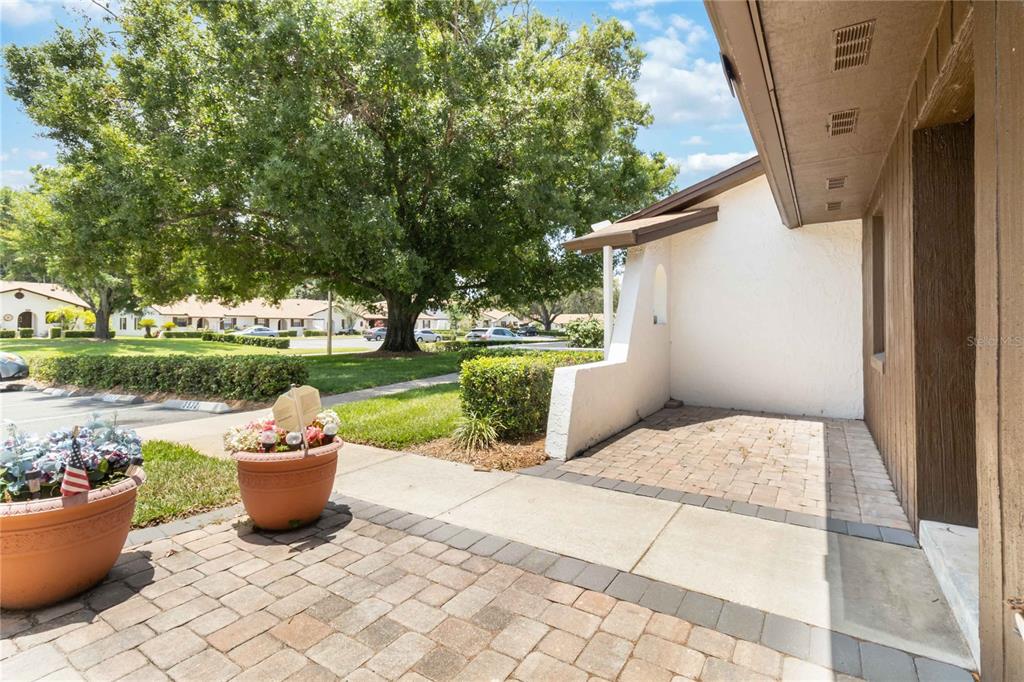 A paved patio area sits in front of a house with white stucco and wood siding — 3528 BAY CT, ST CLOUD, FL