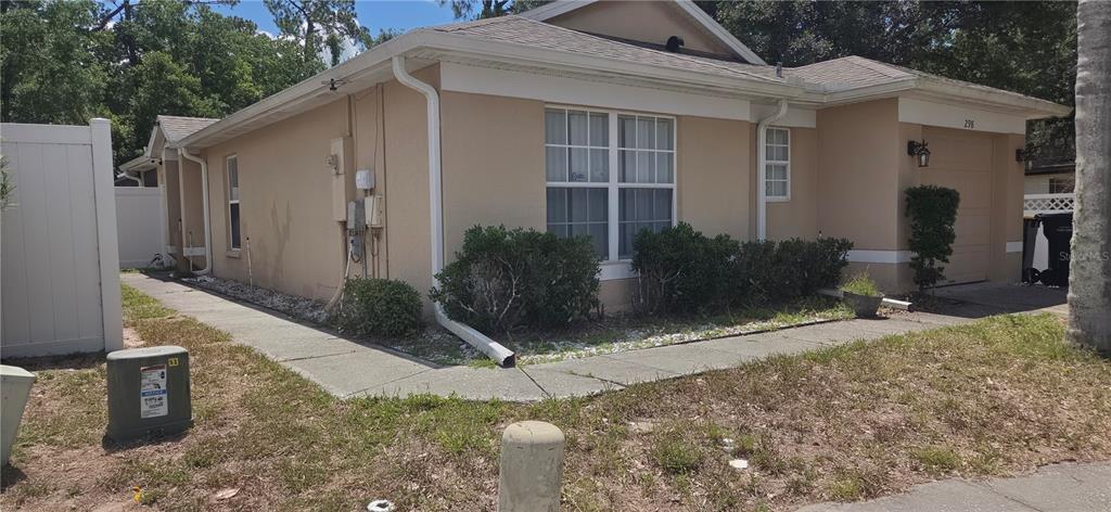 A tan single-story house with a garage, white trim, and a concrete walkway in front — 298 HAMMOCK COURT, DAVENPORT, FL