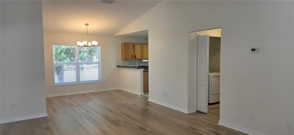 An open-concept living area with light wood-look flooring, a dining space, and a kitchen pass-through — 298 HAMMOCK COURT, DAVENPORT, FL