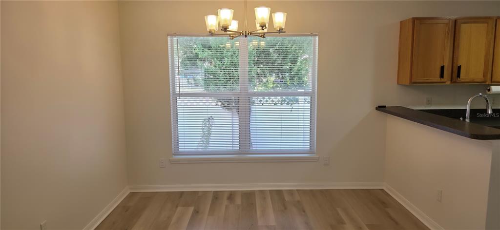 A dining area features light wood-look flooring, a window with blinds, and a chandelier — 298 HAMMOCK COURT, DAVENPORT, FL