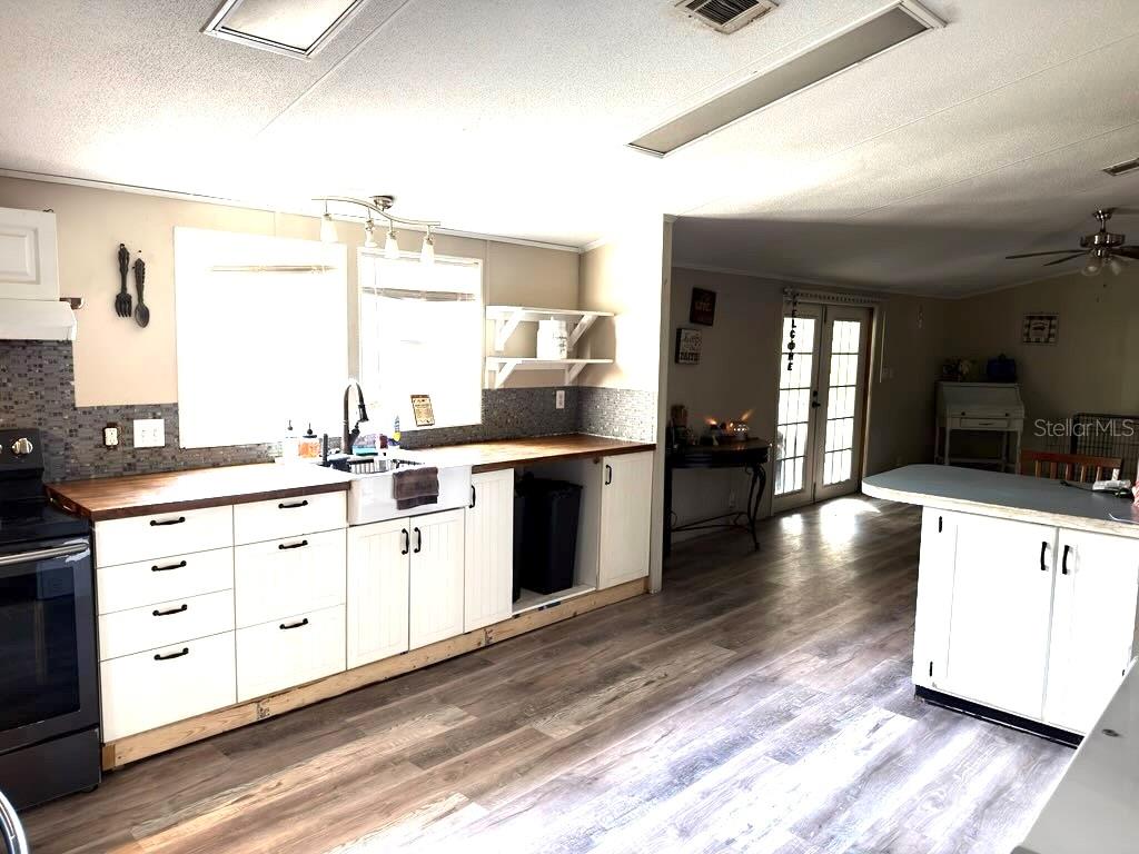 A kitchen features white cabinets, a farmhouse sink, wood countertops, and wood-look flooring — 4126 W BELLA VISTA STREET, LAKELAND, FL