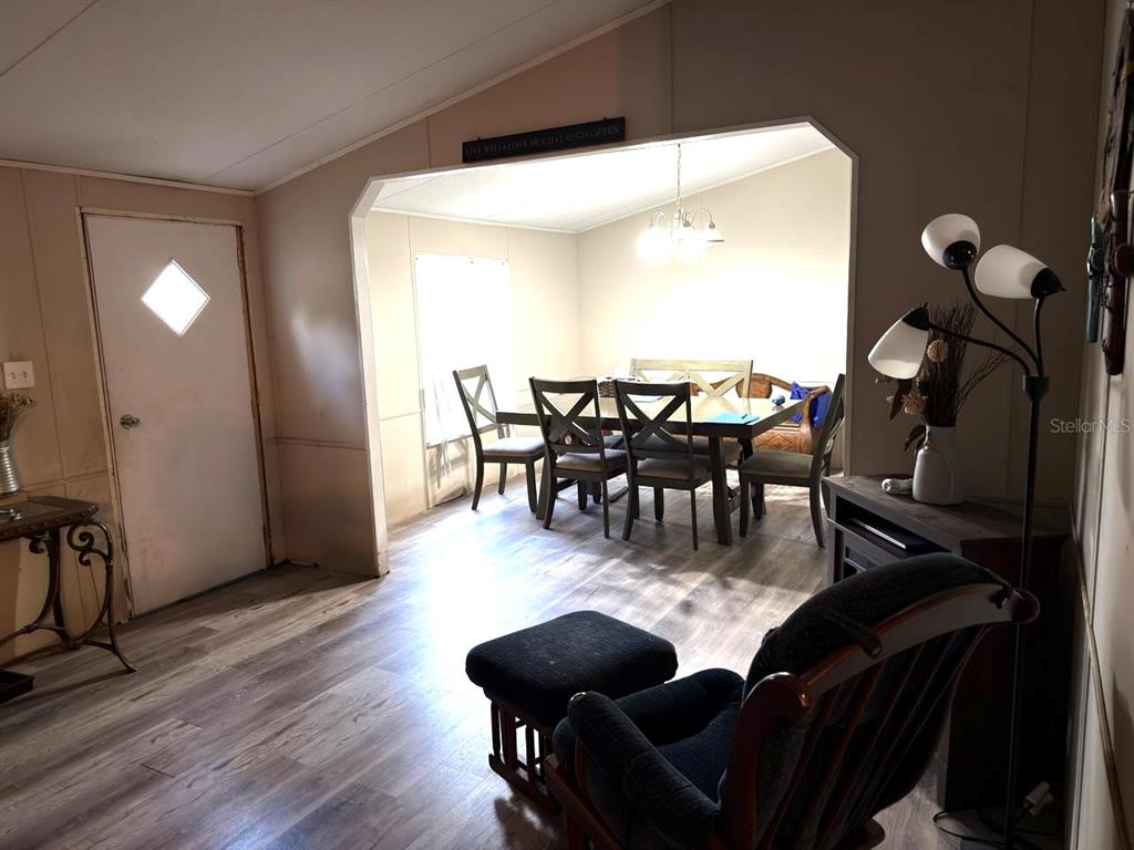 A living room with wood-look flooring leads into a dining area with a table set — 4126 W BELLA VISTA STREET, LAKELAND, FL