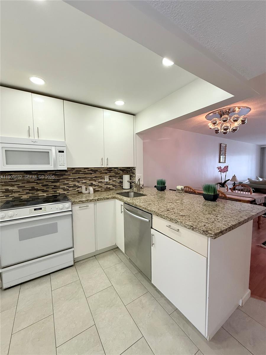 A kitchen features white cabinets, granite countertops, stainless steel appliances, and a tiled floor — 2081 S Ocean Dr # 308, Hallandale Beach FL 33009, HALLANDALE BEACH, FL