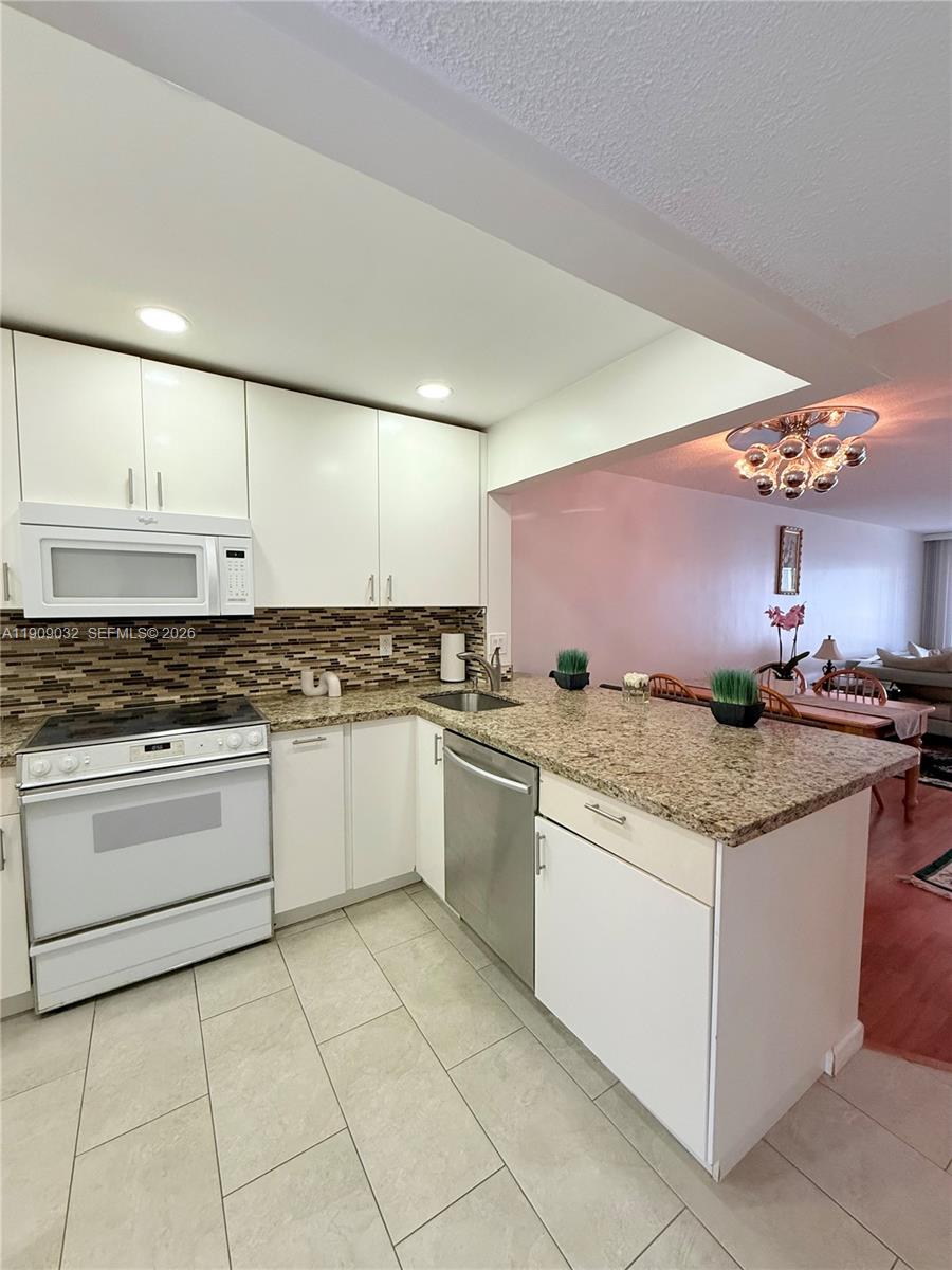 A kitchen features white cabinets, granite countertops, stainless steel appliances, and a tiled floor — 2081 S Ocean Dr # 308, Hallandale Beach FL 33009, HALLANDALE BEACH, FL