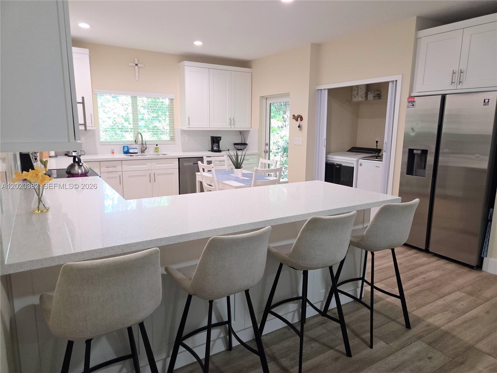 A modern kitchen features a white quartz island, bar stools, and stainless steel appliances — 11 Pompano Ave # 11, Key Largo FL 33037, KEY LARGO, FL