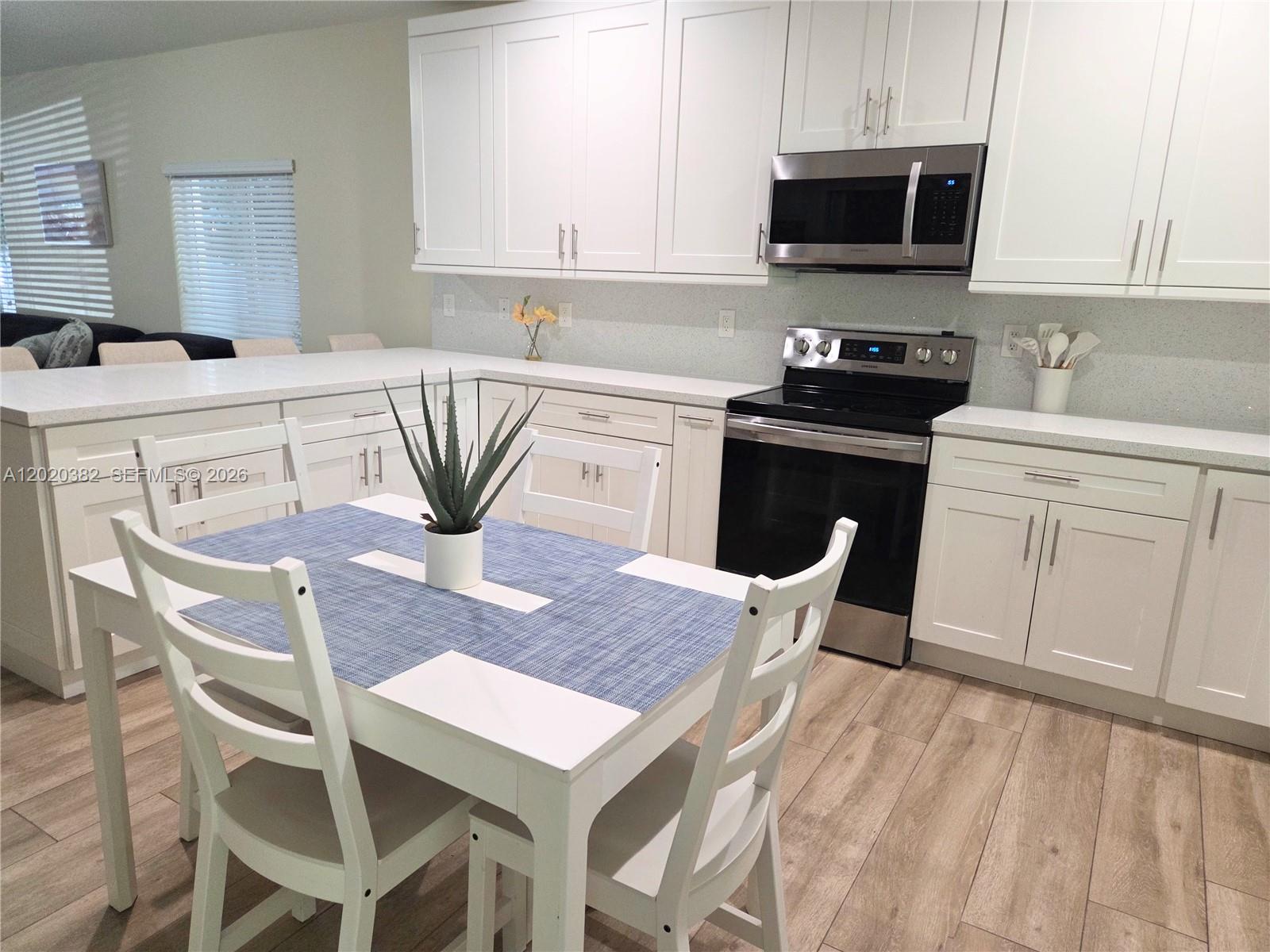 A white kitchen features stainless steel appliances, quartz countertops, and a dining table with chairs — 11 Pompano Ave # 11, Key Largo FL 33037, KEY LARGO, FL