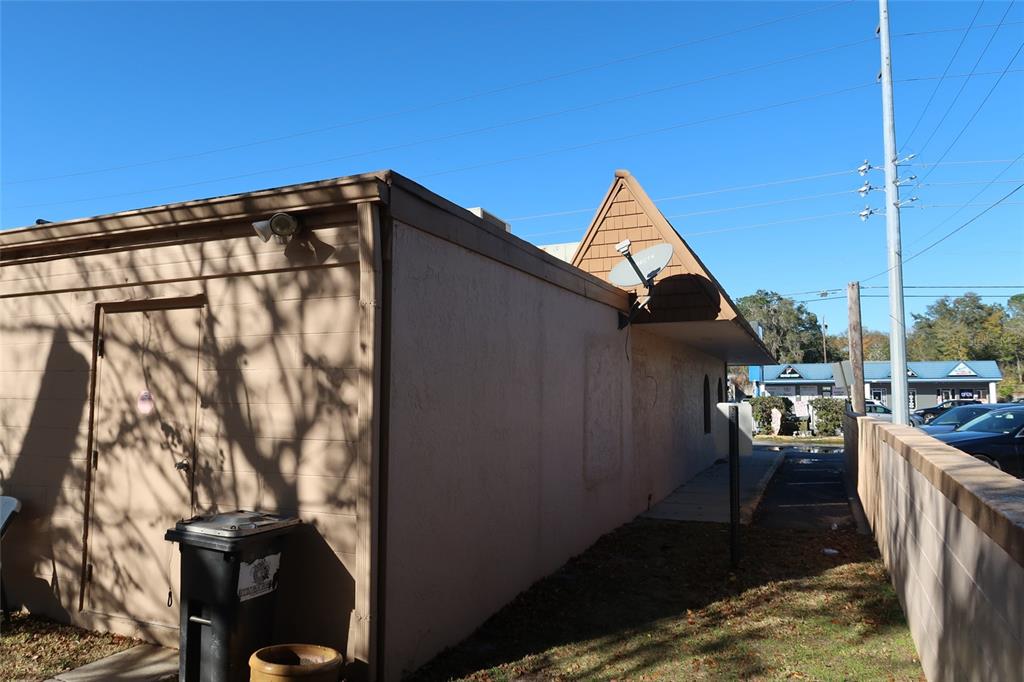The exterior side of a tan building features a door, a trash bin, and a satellite dish — 1170 W STATE ROAD 436, ALTAMONTE SPRINGS, FL