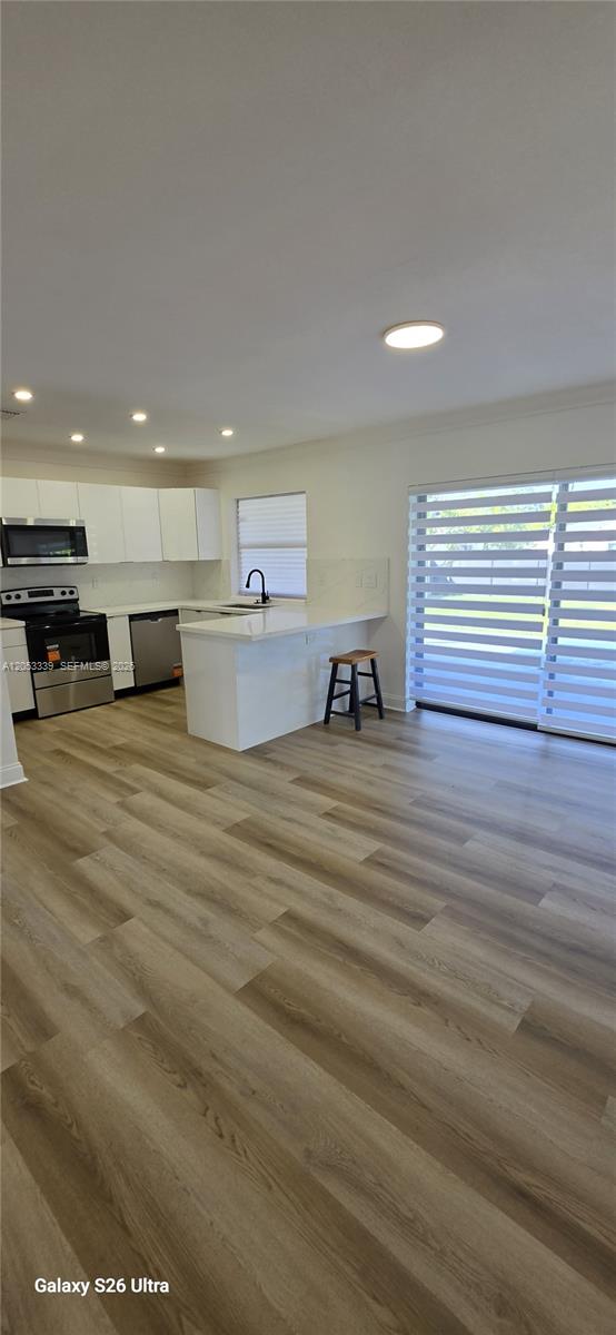 A modern kitchen features white cabinets, stainless steel appliances, and light wood-look flooring — 19225 Franjo Rd, Cutler Bay FL 33157, CUTLER BAY, FL