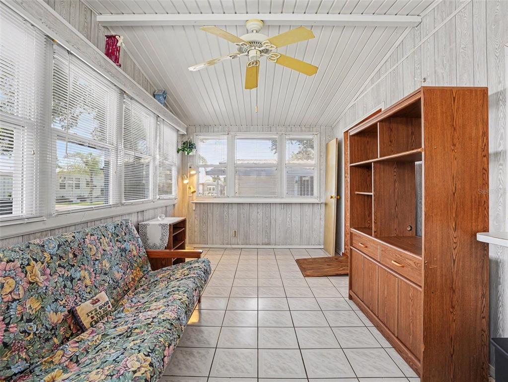 A sunroom features white wood-paneled walls, a tiled floor, a ceiling fan, and floral furniture — 116 PINE TERRACE, HAINES CITY, FL