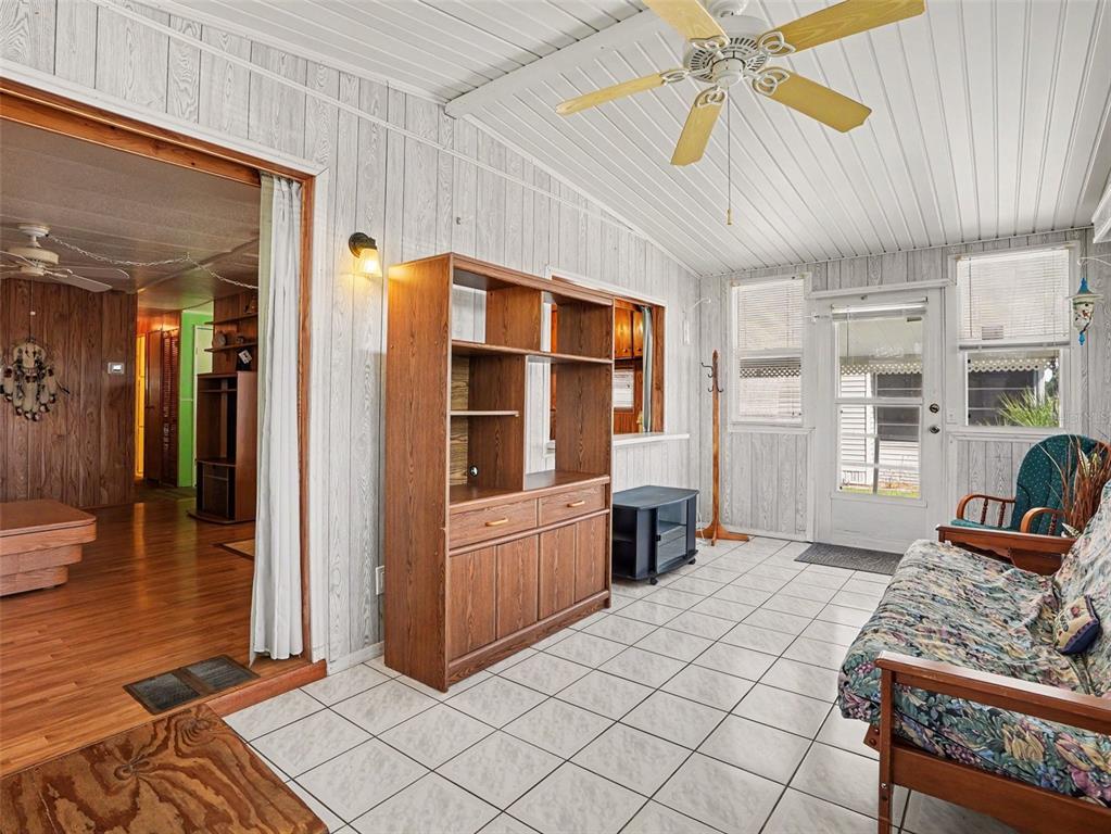 A sunroom features white wood-paneled walls, a tiled floor, a ceiling fan, and a futon — 116 PINE TERRACE, HAINES CITY, FL