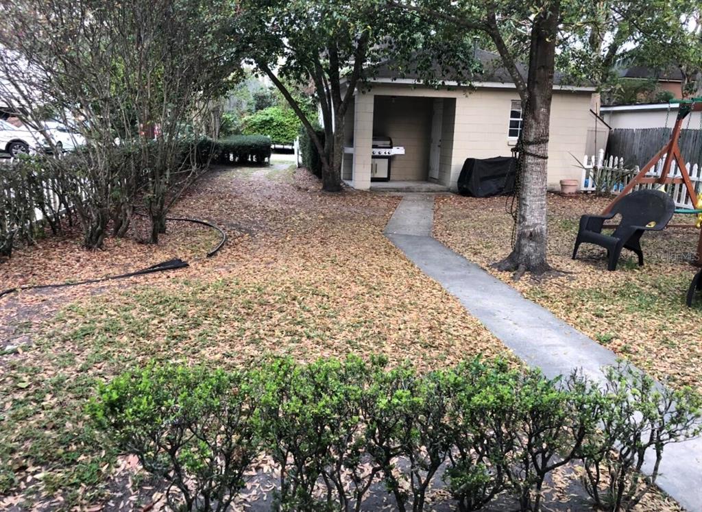 A backyard features a concrete path leading to a detached garage with a covered patio — 826 N WESTMORELAND DRIVE, ORLANDO, FL