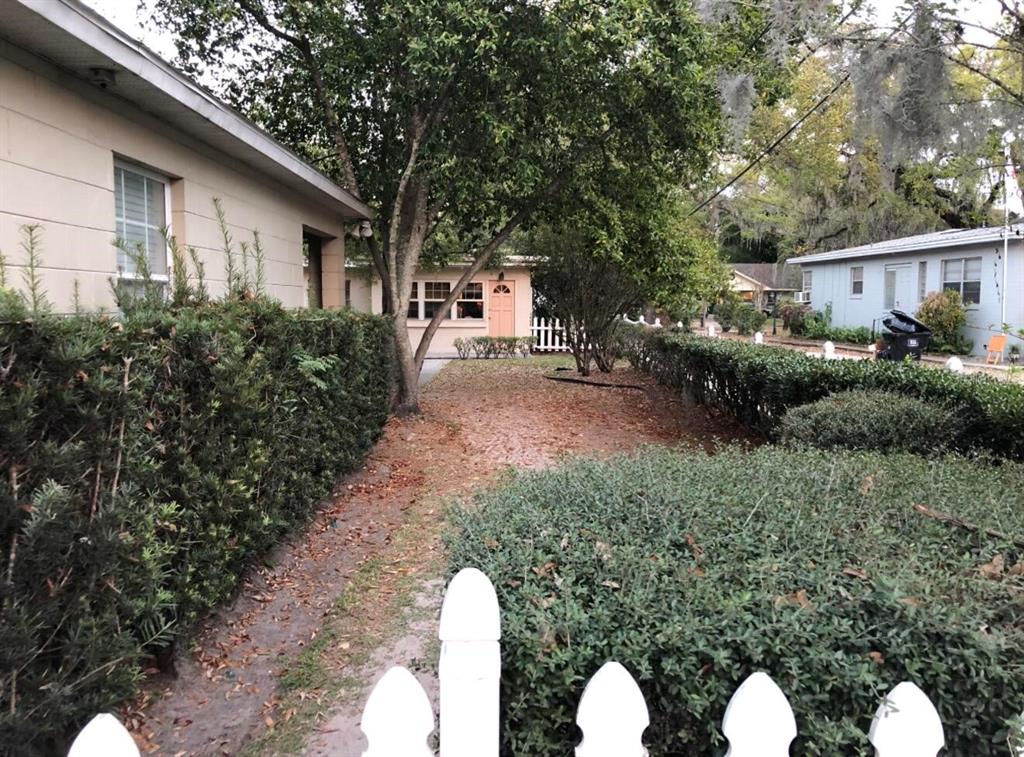 A view of a narrow dirt path between two hedges leading toward a small house — 826 N WESTMORELAND DRIVE, ORLANDO, FL