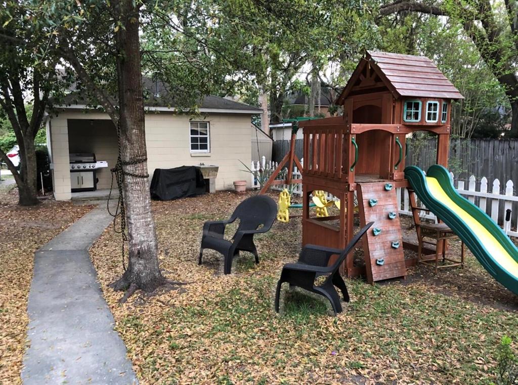 A backyard features a wooden playset with a slide, two black chairs, and a detached garage — 826 N WESTMORELAND DRIVE, ORLANDO, FL