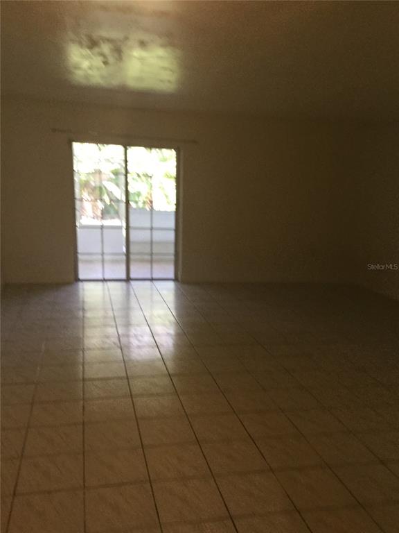 A spacious room with light-colored tile flooring and a sliding glass door leading outside — 2454 RIO PINAR LAKES BOULEVARD, ORLANDO, FL