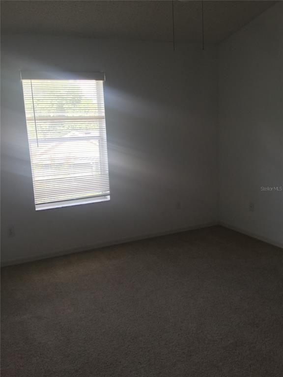 An empty bedroom features beige carpet, white walls, and a window with closed blinds — 2454 RIO PINAR LAKES BOULEVARD, ORLANDO, FL