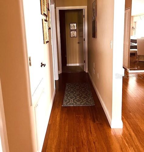 A hallway with hardwood floors leads to an open doorway and a patterned area rug — 9320 CLUBSIDE CIRCLE UNIT 2308, SARASOTA, FL