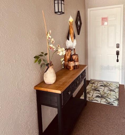 A wooden console table with a pelican statue and floral vase sits by a white door — 9320 CLUBSIDE CIRCLE UNIT 2308, SARASOTA, FL