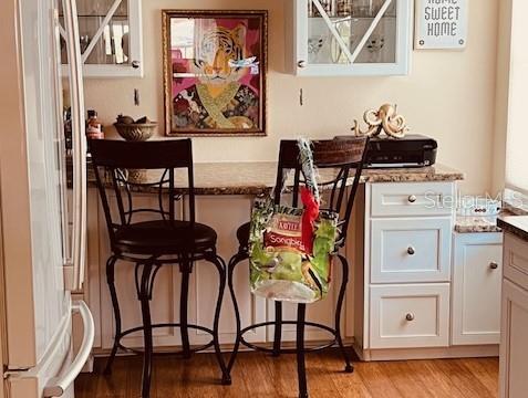 A kitchen breakfast bar features two dark metal stools, white cabinetry, and a tiger-themed wall print — 9320 CLUBSIDE CIRCLE UNIT 2308, SARASOTA, FL