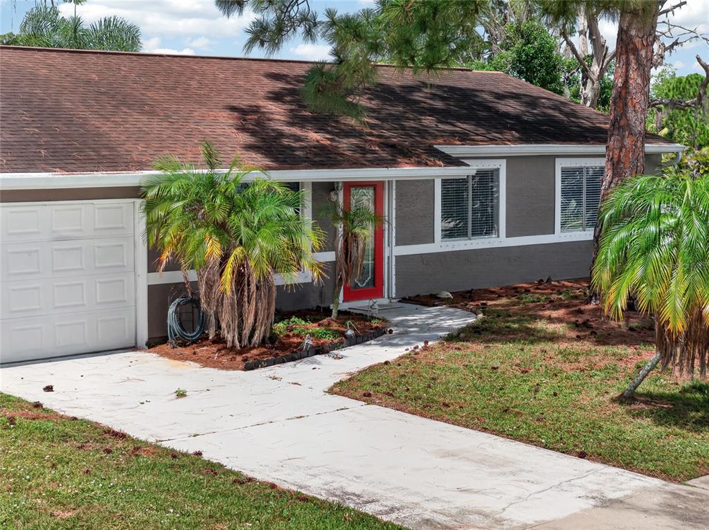 A single-story gray house with a red front door, white trim, and a concrete driveway — 6789 MIRO COURT, NORTH PORT, FL