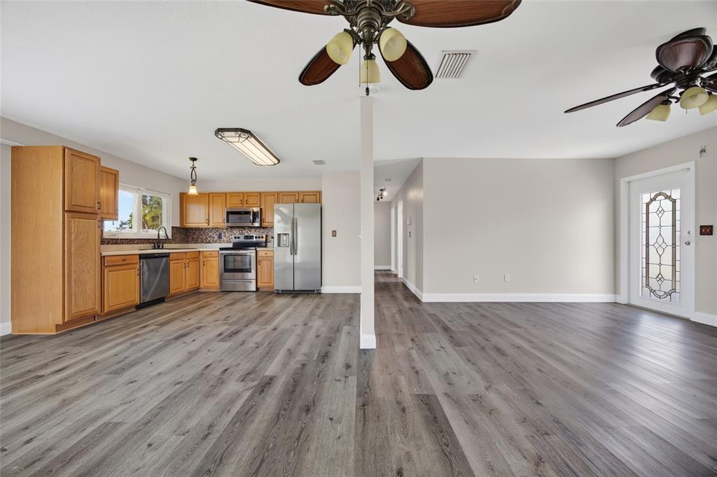 A kitchen with wood cabinets and stainless steel appliances opens to a living area — 6789 MIRO COURT, NORTH PORT, FL