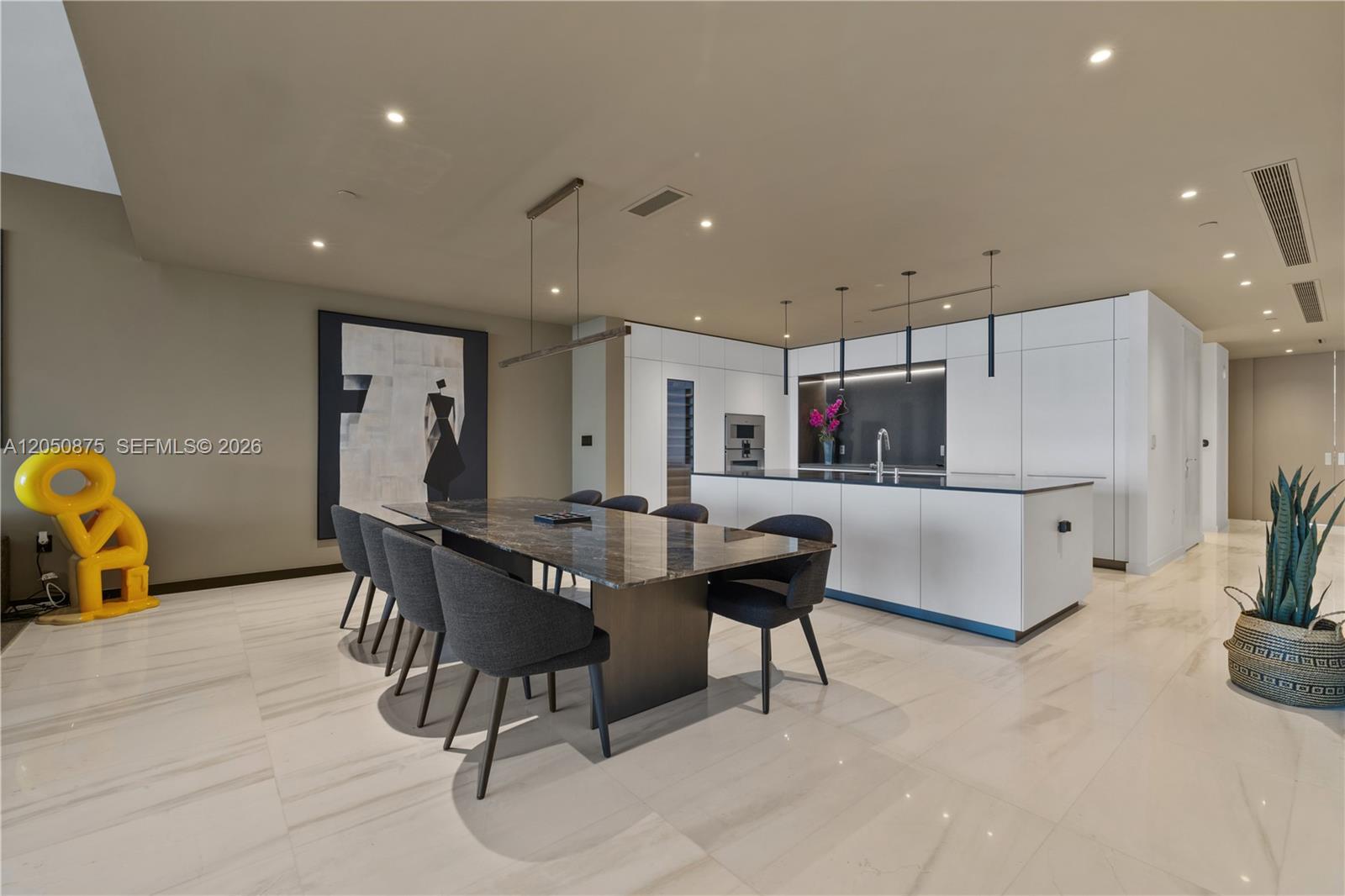 A modern open-concept kitchen and dining area features a marble table and white cabinetry — 300 Biscayne Blvd Way # 3104, Miami FL 33131, MIAMI, FL
