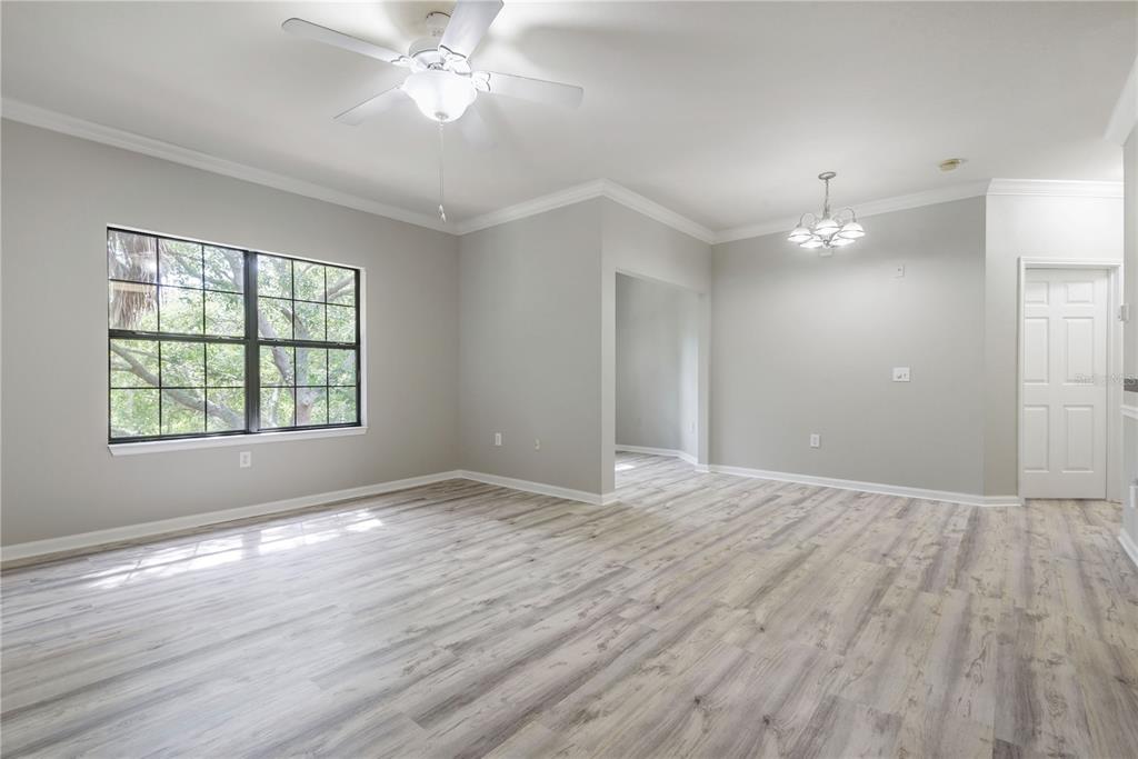 An empty room with light gray walls, wood-look flooring, a ceiling fan, and a chandelier — 2262 CHIANTI PLACE UNIT 5-0526, PALM HARBOR, FL