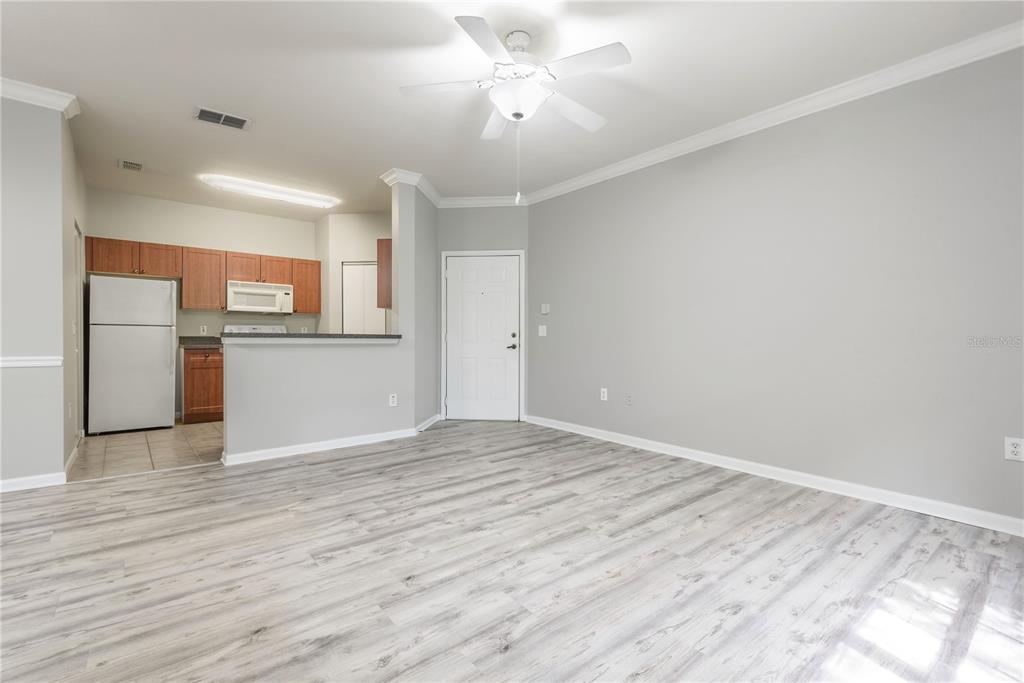 An open-concept living area features light gray walls, wood-look flooring, and an adjacent kitchen — 2262 CHIANTI PLACE UNIT 5-0526, PALM HARBOR, FL