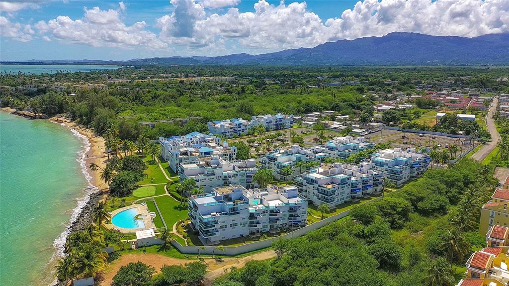 An aerial view of a beachfront apartment complex with a pool and surrounding tropical landscape — 187 km 7 BO. MEDIANIA ALTA UNIT 401, LOIZA, PR