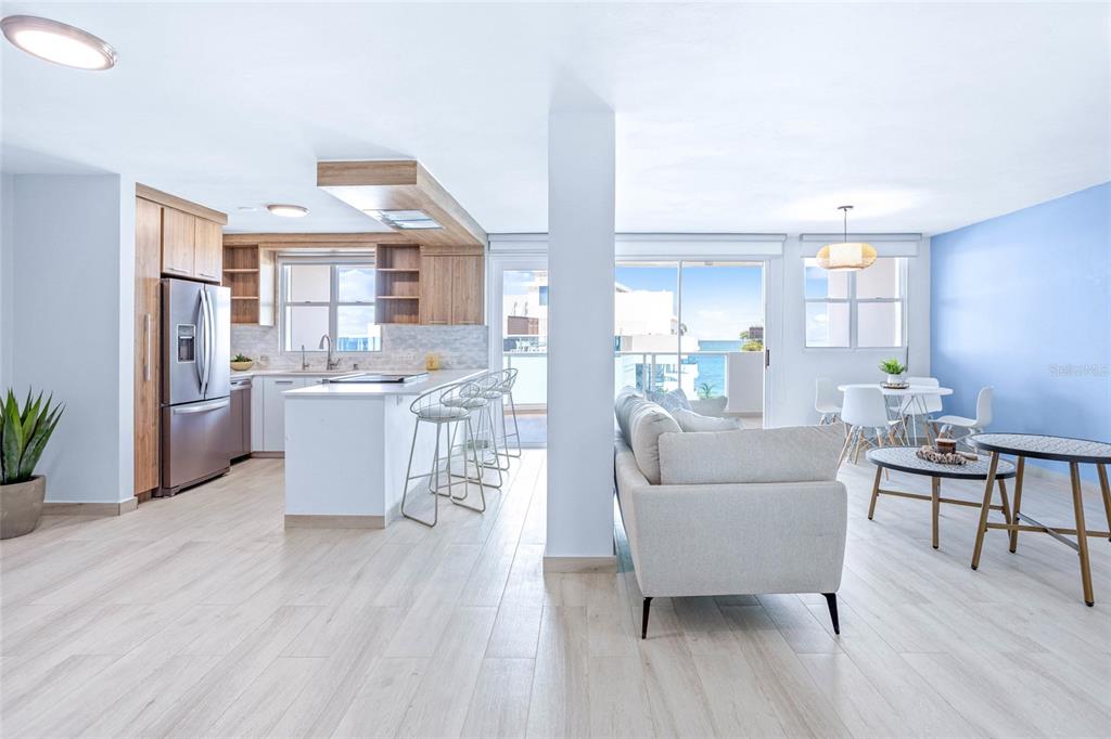 An open-concept kitchen and living area features light wood flooring, a central island, and balcony — 187 km 7 BO. MEDIANIA ALTA UNIT 401, LOIZA, PR