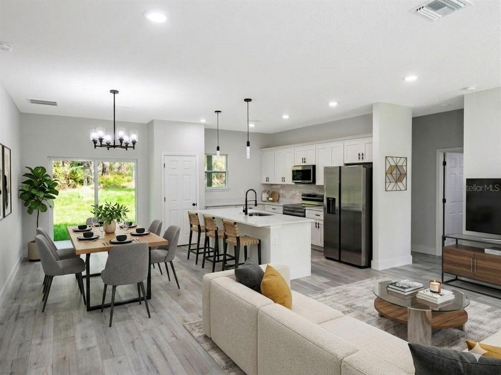 An open-concept kitchen, dining area, and living room with white cabinetry and wood-look flooring — 8649 N ZURICH WAY, CITRUS SPRINGS, FL