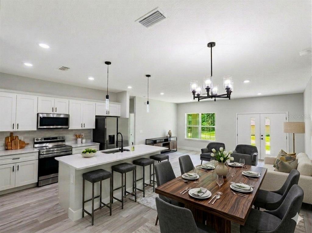 An open-concept kitchen and dining area with white cabinetry, a kitchen island, and wood table — 8649 N ZURICH WAY, CITRUS SPRINGS, FL