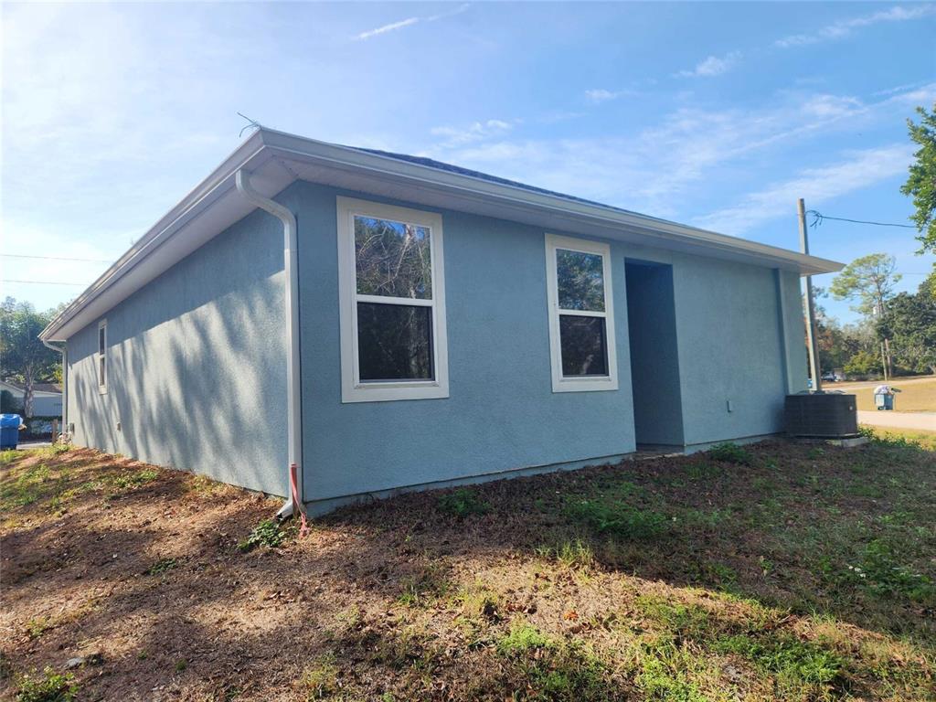 A blue stucco house exterior with white trim and a recessed entryway under a roof — 7369 SEALAWN DRIVE, SPRING HILL, FL