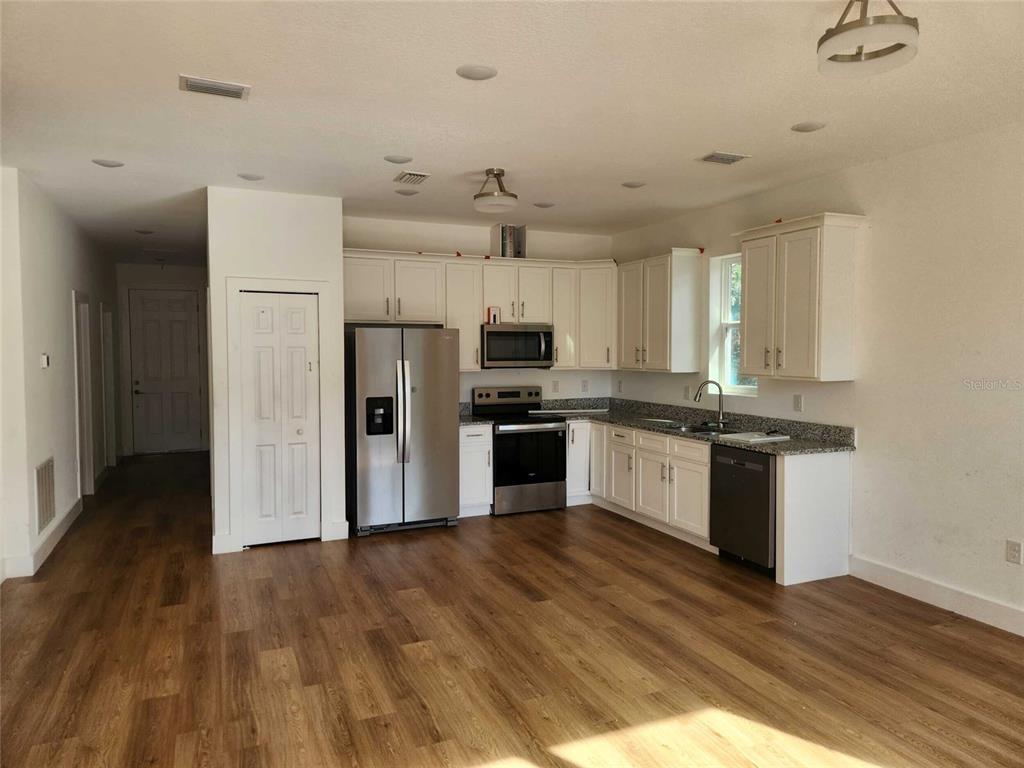 A kitchen with white cabinets, stainless steel appliances, and wood-look flooring — 7369 SEALAWN DRIVE, SPRING HILL, FL