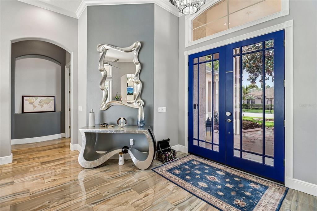 An entryway features a blue double door, a silver console table, and a wavy wall mirror — 5729 OAK LAKE TRAIL, OVIEDO, FL