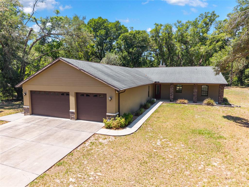 An aerial view of a single-story house with a two-car garage and stone accents — 5190 NW 90TH AVENUE, CHIEFLAND, FL