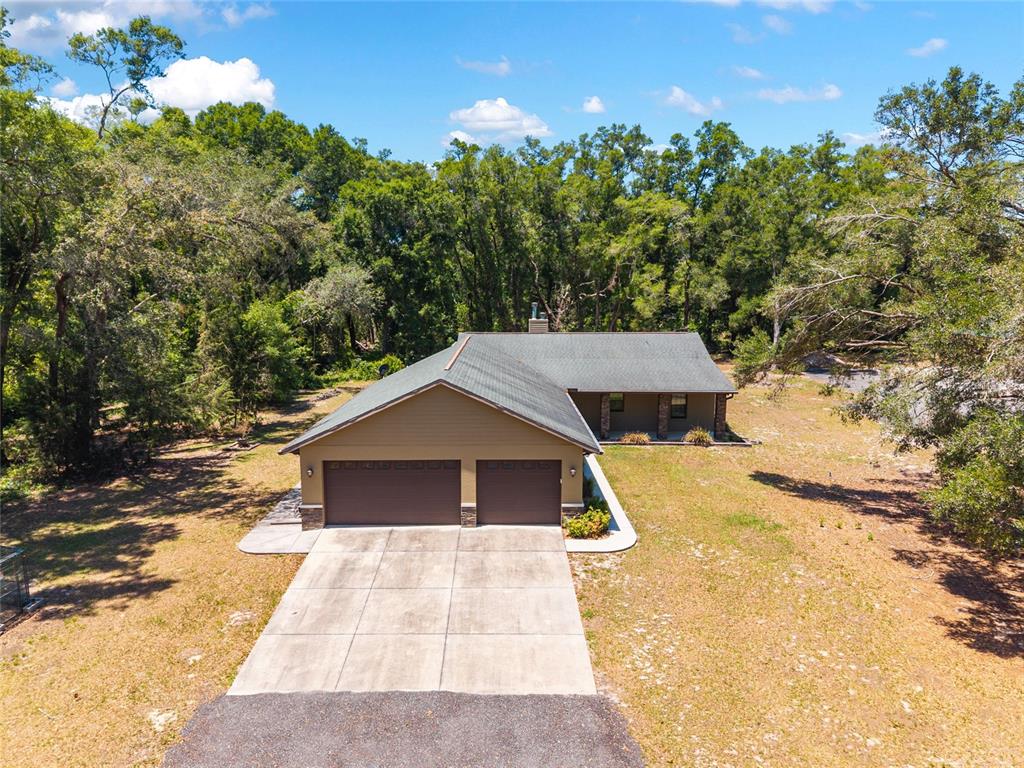 An aerial view of a single-story house with a two-car garage and wooded surroundings — 5190 NW 90TH AVENUE, CHIEFLAND, FL
