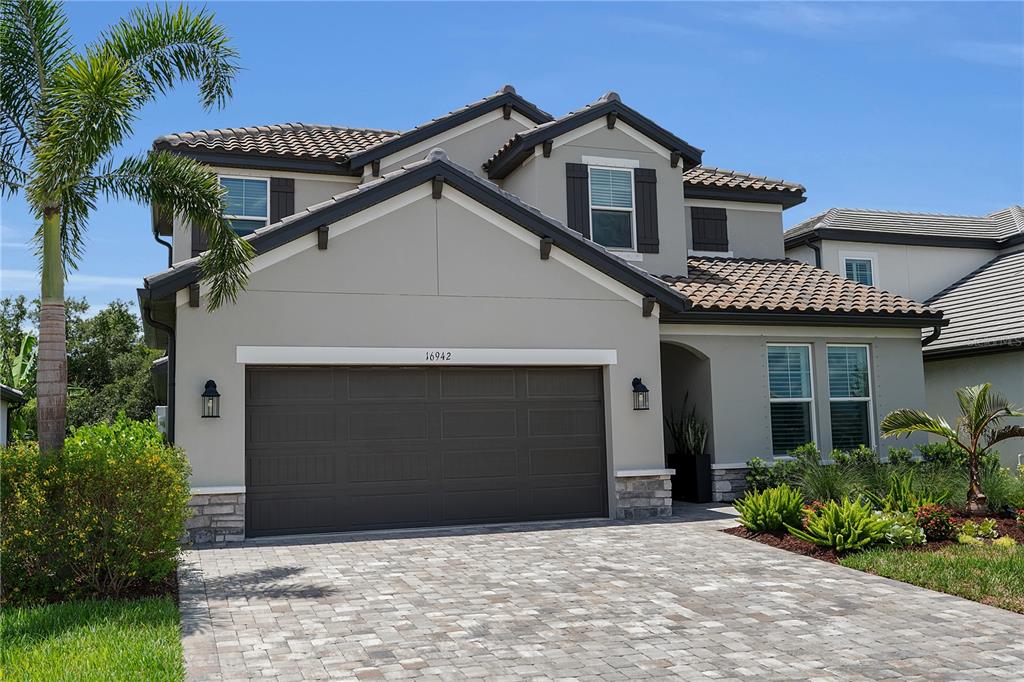 A two-story house with a gray stucco exterior, a tile roof, and a paved driveway — 16942 SAVORY MIST CIRCLE, BRADENTON, FL
