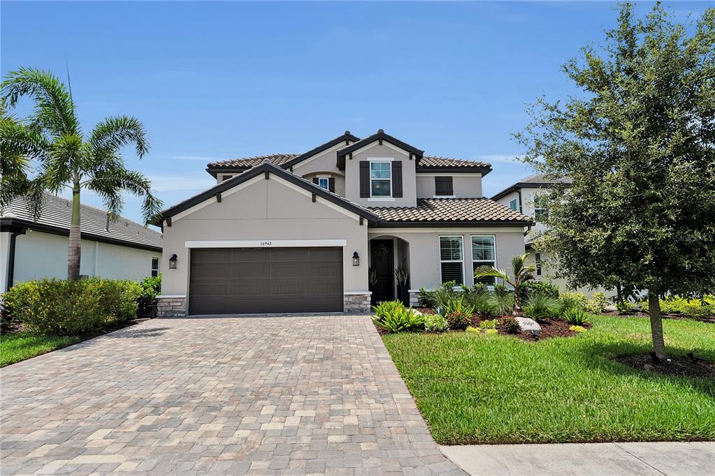 A two-story suburban house with a paved driveway, a two-car garage, and landscaped front yard — 16942 SAVORY MIST CIRCLE, BRADENTON, FL
