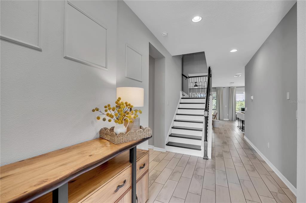 A foyer features a wooden console table, gray walls with molding, and stairs leading upward — 16942 SAVORY MIST CIRCLE, BRADENTON, FL