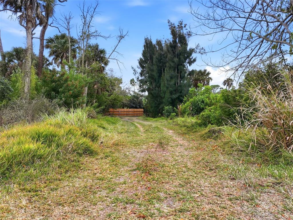 A dirt path leads through a grassy, wooded lot toward a wooden fence — 0 DUNBAR ROAD, VENICE, FL