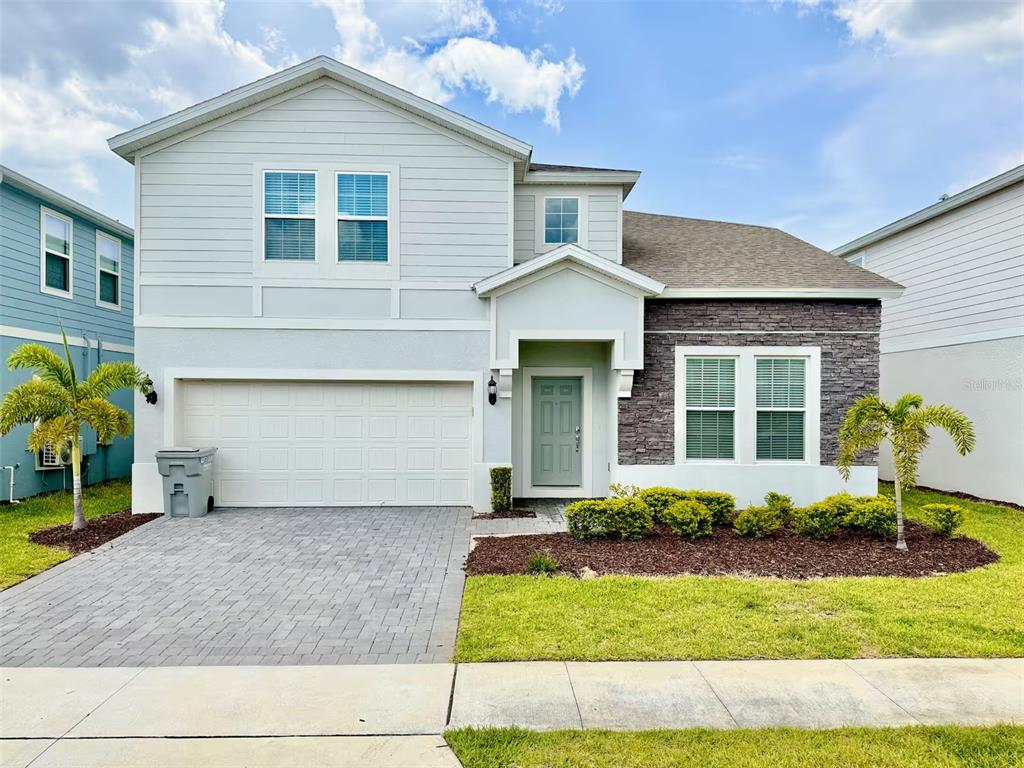 A two-story house with a light-colored exterior, stone accents, a garage, and a front lawn — 4453 KAIPO ROAD, DAVENPORT, FL